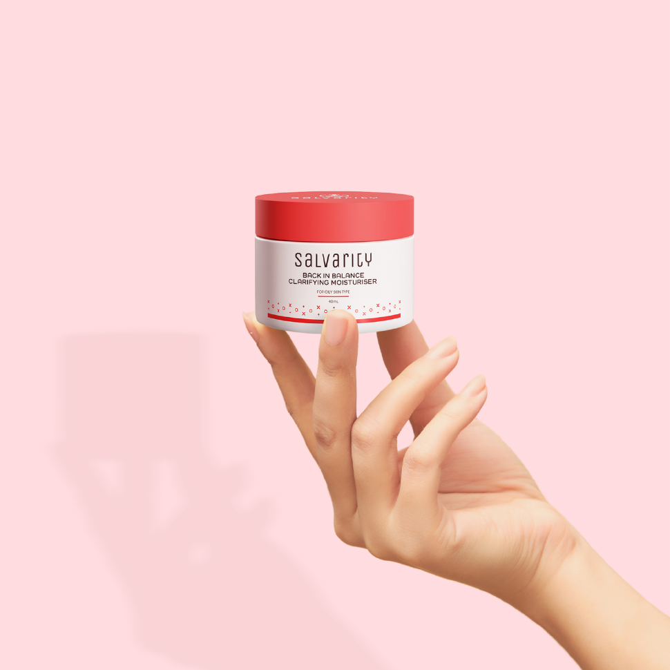 A hand holding a Salvarity Back in Balance Clarifying Moisturizer bottle
